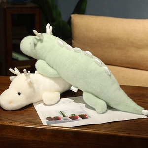 Detail of soft plush dragon pillows in mint green and cream white on a wooden table