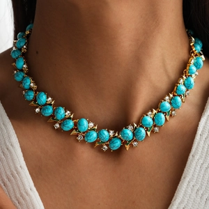 Detail of vintage gold layered necklace with emerald resin and zircon pave accents