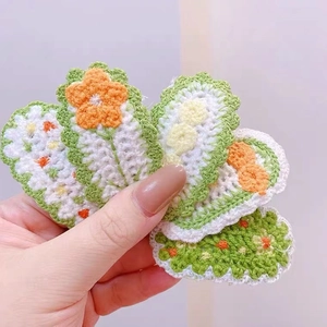 Detailed view of hand-knitted flower hair clips showing crochet textures and yarn patterns