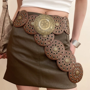 Close-up of bohemian belt featuring embossed bronze metal discs and leather ring charms