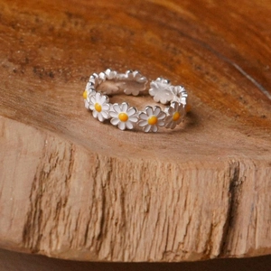 Detail view of silver daisy flower open ring resting on natural textured wood
