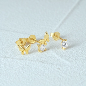 Macro shot of gold butterfly stud earrings set with sparkling white zircon stones