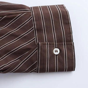 Close-up of brown striped shirt cuff with white button and detailed fabric texture