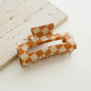 Detail shot of the checkered hair claw clip with orange and cream polished finish