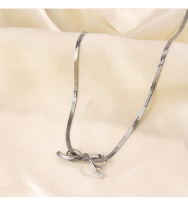 Detailed macro view of silver herringbone snake chain featuring a polished bow pendant