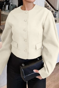 Detail view of beige puff-sleeve cropped jacket with single-breasted buttons and faux pockets