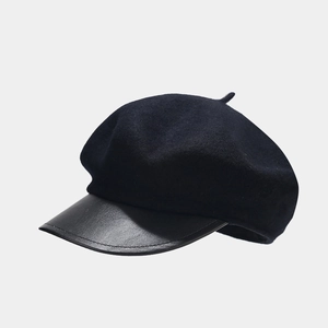 Detail of vintage black newsboy cap featuring textured wool and matte leather brim