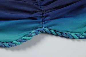 Détail du tissu dégradé bleu-vert avec design froncé et bordure tressée élégante