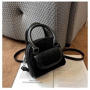 Detail of black suede and faux fur patchwork handbag on a vintage book and rug