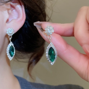 Detail of silver drop earrings with emerald green stones and floral crystal design