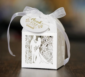 Macro detail of laser-cut Mr & Mrs wedding candy box with thank you tag and white ribbon