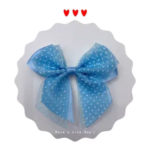 Close-up of a light blue tulle bow hair clip with white polka dots on a card
