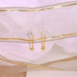 Detail view of gold tassel chain earrings with shimmering white cubic zirconia stones