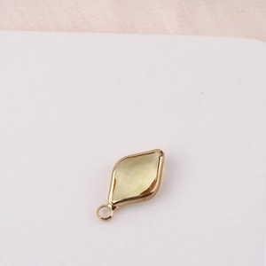 Macro shot of rhombus yellow crystal pendant with gold-plated frame for DIY jewelry