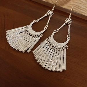 Detail of silver bohemian tassel earrings featuring floral accents and crescent moon charms