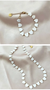 Detailed view of gold stainless steel necklace and bracelet set with shell heart beads