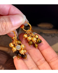 Detail of tiger eye stone and zircon tassel earring with matte gold beads on gold base