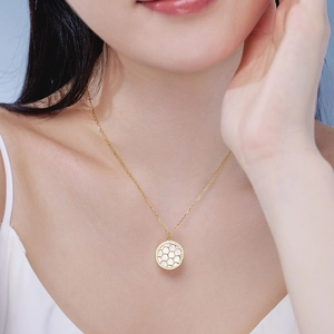 Detail of model wearing a golden honeycomb necklace featuring white mother of pearl inlay