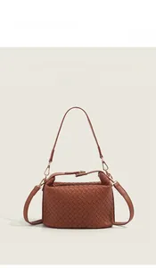 Detail of woven crossbody bag showing leather texture and magnetic metal clasp