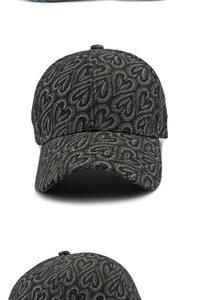 Détail du motif jacquard à cœurs sur le tissu en denim gris de la casquette de baseball