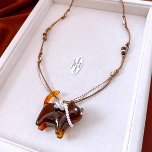 Close-up detail shot of an amber-colored resin cat necklace pendant with faux pearl accents