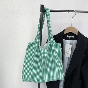 Detail of green and white plaid canvas tote bag hanging on a rack for daily use