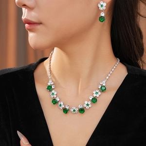 Close-up of floral necklace with emerald green stones and white zircon on a model