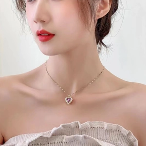 Detailed view of model wearing a gold titanium necklace with a purple heart-shaped pendant