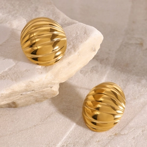 Elegant gold chunky ribbed oval earrings on natural stone background with metallic luster