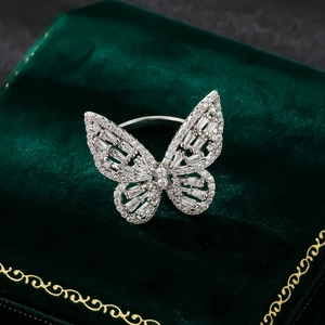 Close-up of a silver butterfly ring with sparkling zircon stones on green velvet