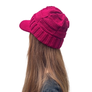 Détail du bonnet à visière en maille rose rouge avec tissage thermique épais torsadé