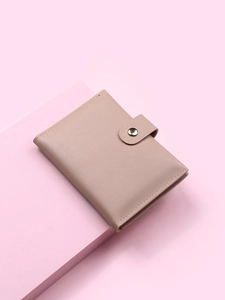 Detail view of pink PU leather card holder wallet with snap button closure on pedestal
