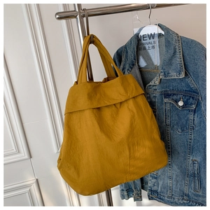 Detail of a bright yellow nylon tote bag with unique fold-over design and lightweight fabric