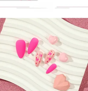 Detail of pink stiletto press on nails with matte finish and heart pattern