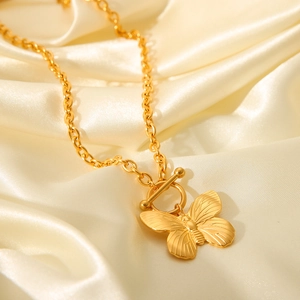 Detail of golden butterfly pendant with OT buckle on smooth beige silk background