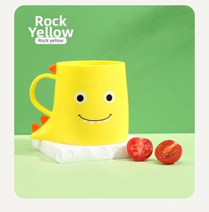 Close-up of rock yellow dinosaur mug with cute cartoon face and orange dorsal fins detail