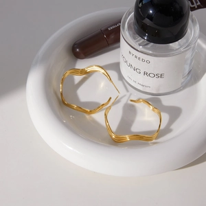 Classic 18K gold plated stainless steel wavy hoop earrings on white ceramic tray