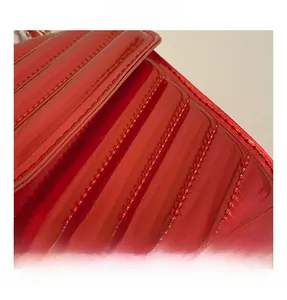 Macro shot of red patent leather with V-shaped quilted texture and fine stitching