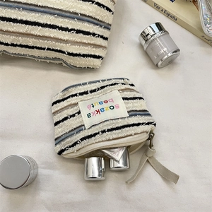 Macro detail of striped fabric makeup bag with frayed edges and sozakka label