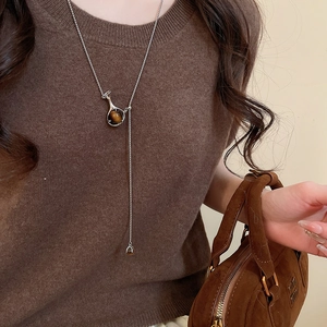 Detailed view of silver Y-shaped necklace featuring a brown tiger eye stone pendant