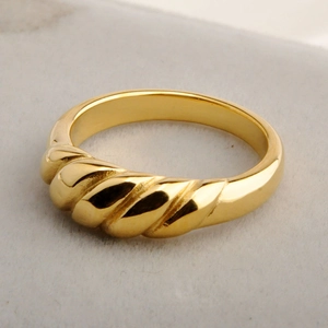 Golden croissant dome ring with minimalist twisted thread design on grey background