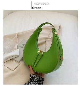 Detail of lime green hobo bag with gold hardware on a beige blazer background