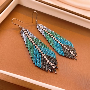 Macro view of crystal feather earrings with blue and green gradients in a jewelry box