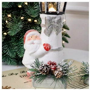 Detail of Santa Claus figure with warm LED lantern and pine cone holiday decoration