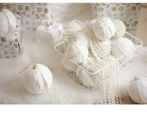 Detail of white Christmas ornaments set featuring velvet balls and pearl beads in a metal basket