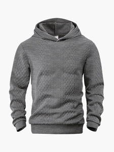Detail eines dunkelgrauen Kapuzenpullovers mit 3D-Rautenstrick und Jacquard-Gewebe