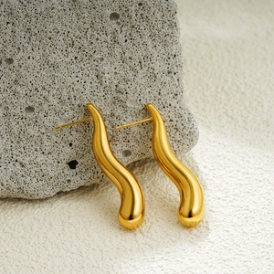 Detail of 18K gold water drop earrings with sleek curved lines on natural stone