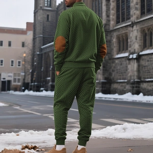 Men's dark green knit tracksuit with high neck zipper and elbow patches in outdoor setting