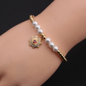 Close-up of gold-plated beaded bracelet with pearl accents and a star sunburst charm