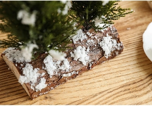 Macro detail of artificial pine needles with faux snow on a natural wood base for Christmas